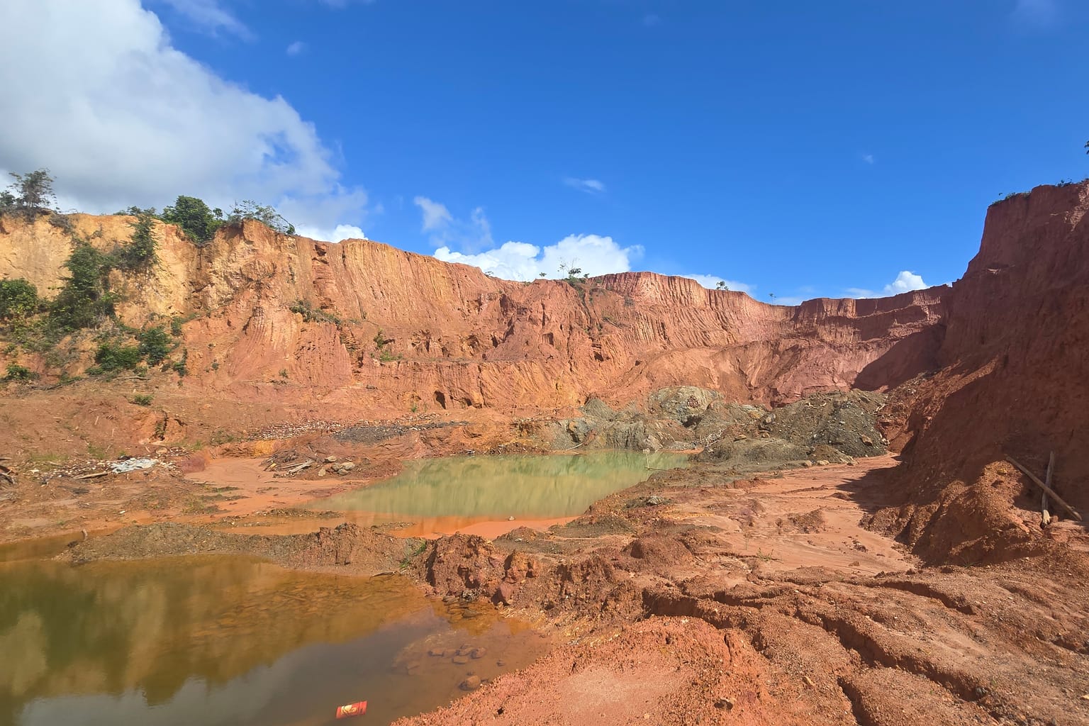 Red laterite cliffs above a turquoise pond at the Big Berg discovery, Sela Creek